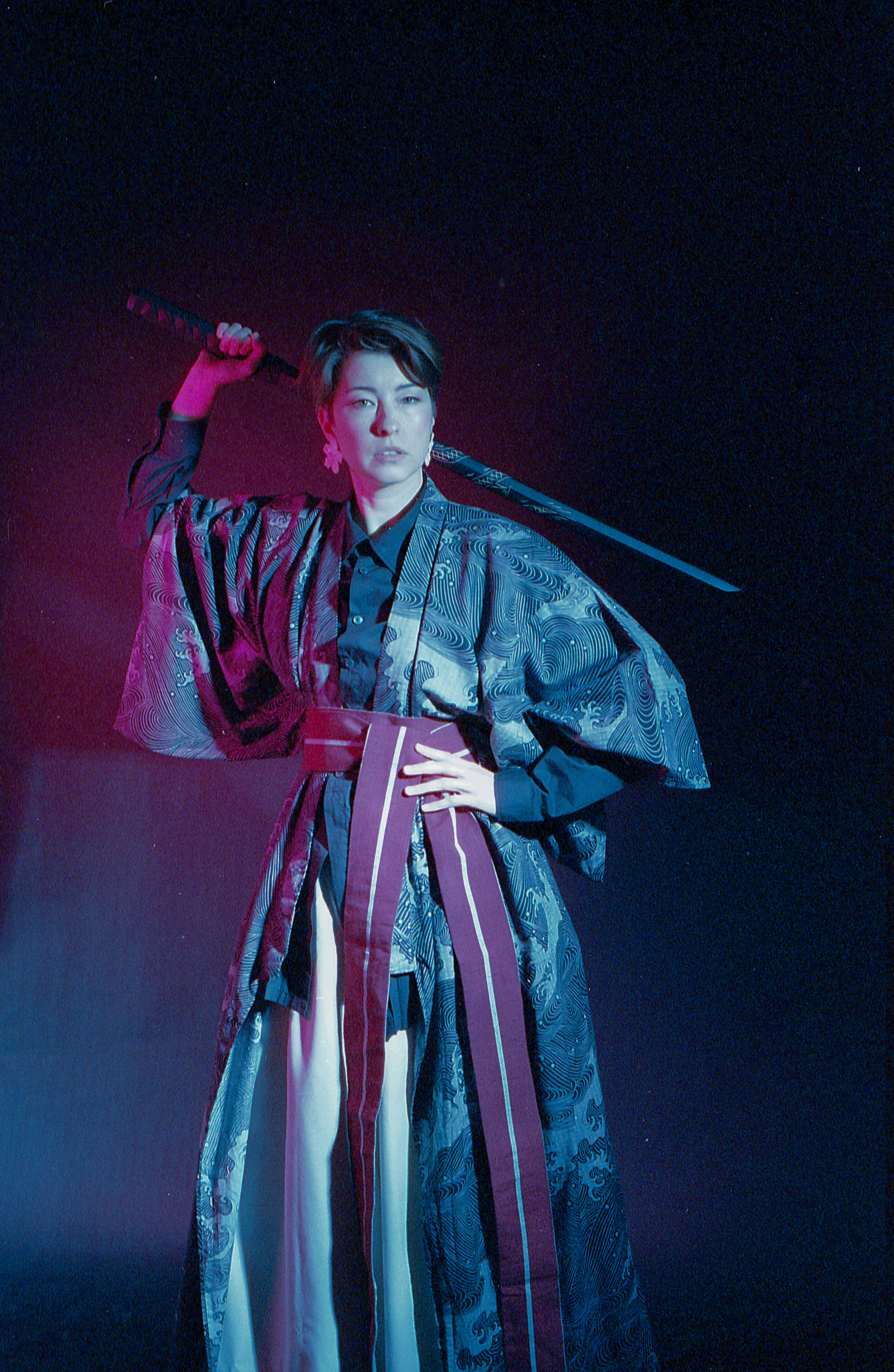 Yulia drawing the katana overhead in pink and blue light